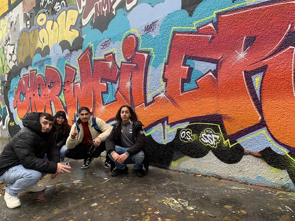 Jugendliche vor einem Graffiti mit dem Schriftzug Chorweiler