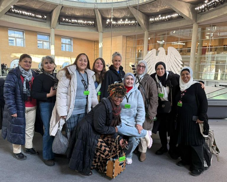 Gruppenbild von 10 Frauen auf der Besuchertriüne des deutschen Bundestages, im Hintergrund ist der Plenarsaal mit dem Bundesadler zu erkennen.